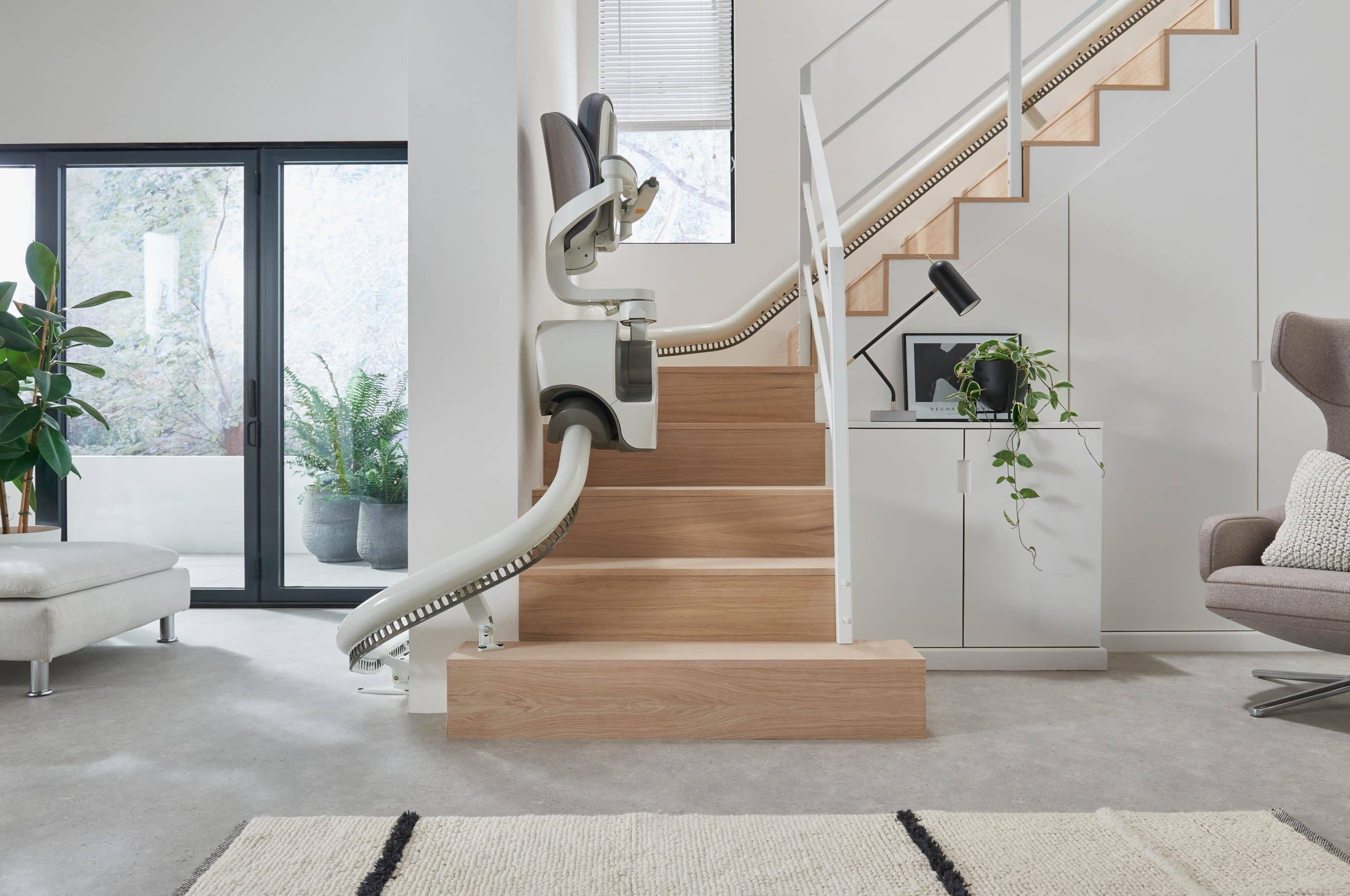 Image is of a FlowX curved stairlift parked up the stairs
